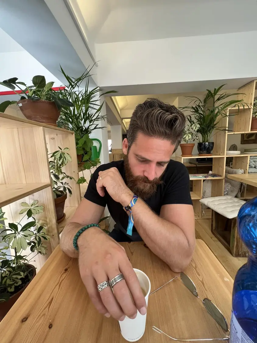 אמיר גיגי יושב בשקט בבית קפה עם צמחים
